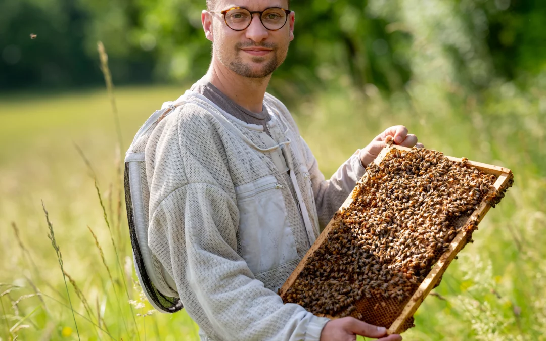Benoit Serre, apiculteur du Rucher du Marandou en Dordogne, tenant un cadre de ruche rempli d’abeilles