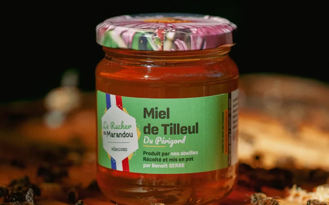 Pot de miel de tilleul du Périgord 250 g posé sur une ruche avec des abeilles